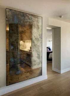 a large painting hanging on the wall next to a bed in a room with hardwood floors