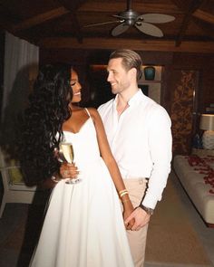 a man standing next to a woman holding a glass of wine in front of her