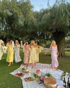 a group of women standing on top of a lush green field next to a tree