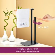 the towel rack has two towels on it and is next to a vase with flowers