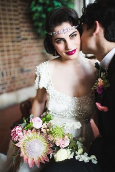 a bride and groom kissing in front of a window