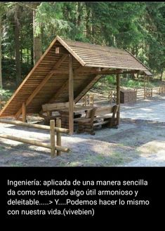 a wooden shelter sitting in the middle of a forest next to a picnic table and benches