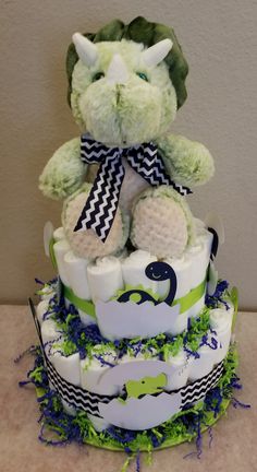 a green and white diaper cake with a stuffed animal sitting on top of it