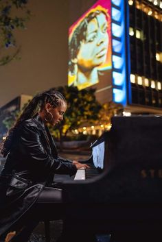 a woman sitting at a piano in front of a building