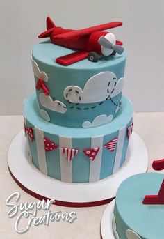 a blue and white cake with a red airplane on top, next to another one