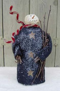 a small figurine is standing in front of a wooden fence with snow on it