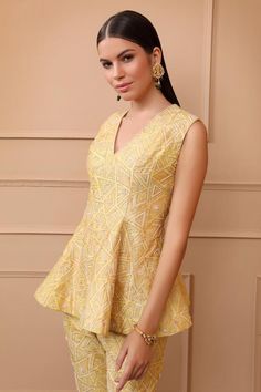 Yellow sleeveless digital printed peplum top with exquisite gold thread, pearl embroidery in geometric pattern. Paired with flared pant.
Components: 2
Pattern: Digital Printed, Embroidery
Type Of Work: Thread, Pearl, Geometric
Neckline: V neck
Sleeve Type: Sleeveless
Fabric: Dupion
Color: Yellow
Other Details: 
Model height: 5ft 8inches, wearing size XS
Occasion: Sangeet - Aza Fashions Elegant Tops With Chikankari Embroidery For Reception, Elegant Top With Chikankari Embroidery For Reception, Elegant V-neck Tops With Zari Work, Elegant V-neck Top With Zari Work, Fitted Embellished Peplum Palazzo Set, Embellished Fitted Peplum Palazzo Set, Fitted V-neck Sets With Resham Embroidery, Yellow Chikankari Embroidered Festive Top, Festive Yellow Top With Chikankari Embroidery