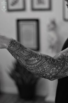 a man with a tattoo on his arm holding something in one hand and looking at the other