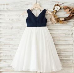 a white and blue dress hanging on a wooden wall next to a dried flower wreath