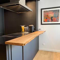 the kitchen counter is made out of wood and has a painting on the wall above it