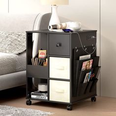 a small black and white storage unit with magazine holders on wheels next to a couch