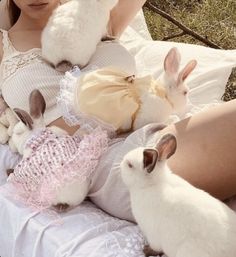 a woman in white dress sitting next to rabbits