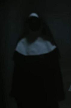 a person standing in the dark with their back turned to the camera and wearing a black cloak