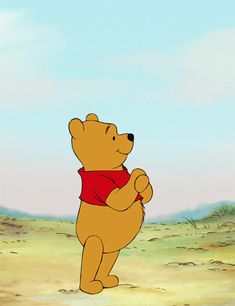 winnie the pooh is standing on his hind legs and holding onto a red scarf