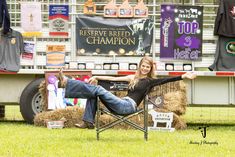 a woman sitting in a chair on top of a grass covered field next to a truck