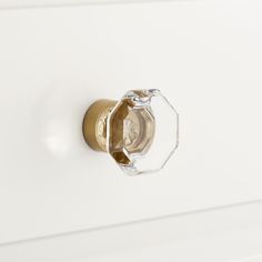 a close up of a knob on a white cabinet with gold handles and glass inserts