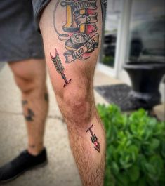 a man's leg with tattoos on it and an arrow in the middle of his leg