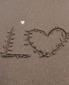 i love you written in the sand with a white heart on it's side