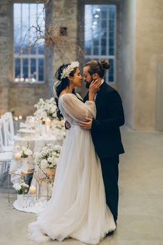 a bride and groom standing next to each other in front of a table with candles