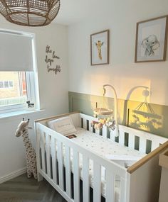 a baby crib in the corner of a room with pictures hanging on the wall