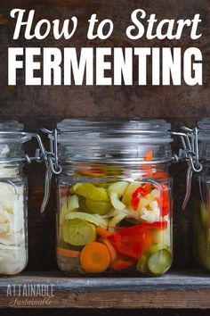 four mason jars filled with pickles, carrots and celery sitting on top of a wooden shelf