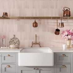 a kitchen with pink wallpaper and gold accessories on the shelf above the white sink