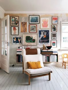 a living room with pictures on the wall and a chair in front of a door