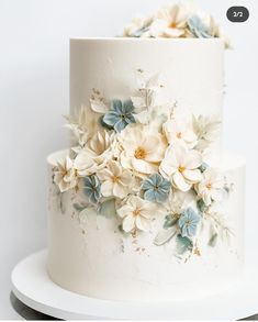 a white and blue wedding cake with flowers on it