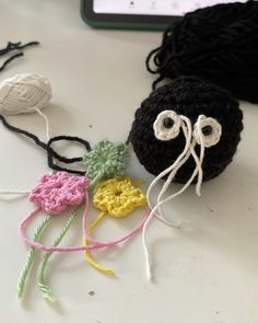 crocheted balls of yarn with eyes on them sitting next to a cell phone