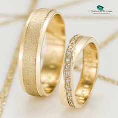 two gold wedding bands with diamonds on them sitting next to each other in front of a white background