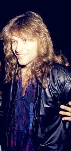 a man with long hair wearing a leather jacket