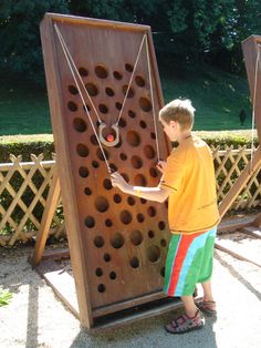 a young boy is playing giant connect the dots game in front of a wooden fence