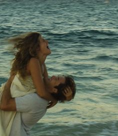 a man carrying a woman on his back at the beach