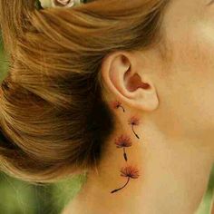 a woman's ear has a dandelion tattoo on it