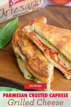 the grilled cheese sandwich is cut in half on a cutting board with basil leaves