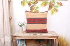 a pillow sitting on top of a wooden table next to a vase with flowers in it