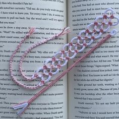 an open book with pink and white beads on it's cover, next to a pair of scissors