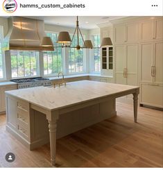 a large kitchen with an island in the middle and two pendant lights hanging from the ceiling