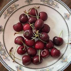 a white bowl filled with cherries on top of a wooden table