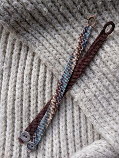 a knitted sweater with two metal buttons attached to it