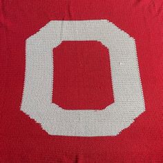 a red and white knitted blanket with the letter o on it