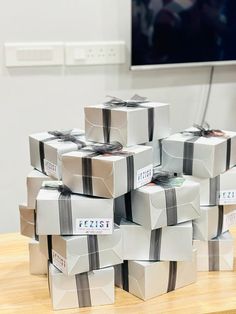 a stack of wrapped presents sitting on top of a wooden table next to a flat screen tv