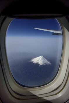 an airplane window looking out at the snow capped mountain