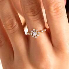 a woman's hand with a diamond ring on top of her finger and the other hand holding an engagement ring