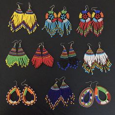 six pairs of beaded earrings are displayed on a black surface, including one with fringes and the other with beads