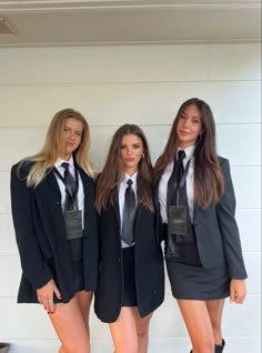 three young women dressed in school uniforms posing for the camera with one woman wearing short shorts