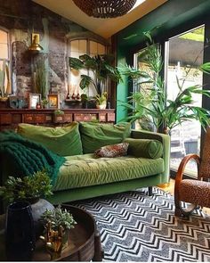 a living room filled with lots of green furniture and plants on top of the couches