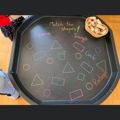 a child's chalk board with different shapes and words written on it, sitting on the floor