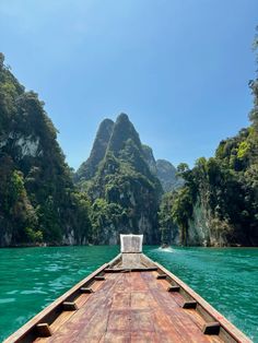 the back end of a boat traveling down a river with mountains in the far distance