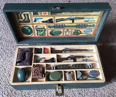 an open suitcase filled with assorted items on carpeted floor next to wallpaper